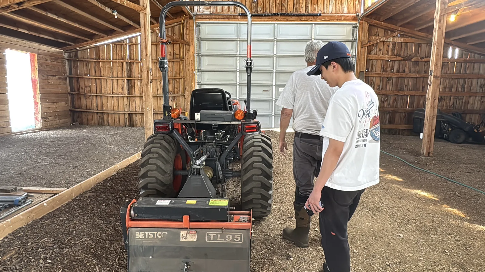 Jack Huang and Stephen beside a tractor inside a barn at Splendor Valley Farms.